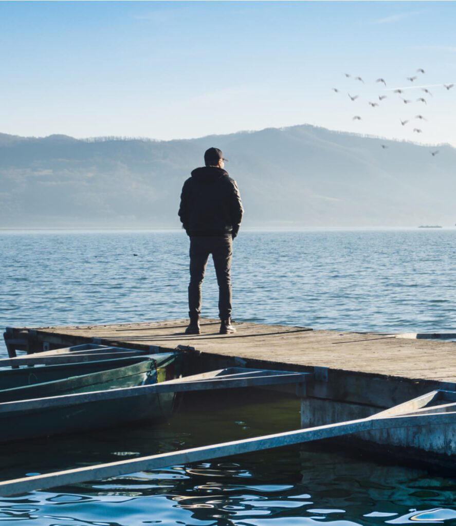 A man sits alone on a floating pontoon and contemplates the landscape